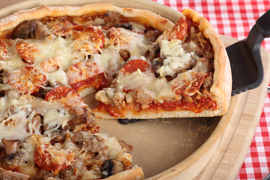 Slice of deep dish sausage and pepperoni pizza in a pizza pan